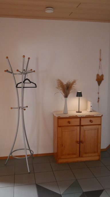 Garderobe mit Hutständer, Holzschrank und Tischlampe in einem Raum.