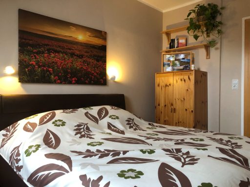 Schlafzimmer mit einem Bett, einer Blumenwand und einem Holzschrank.